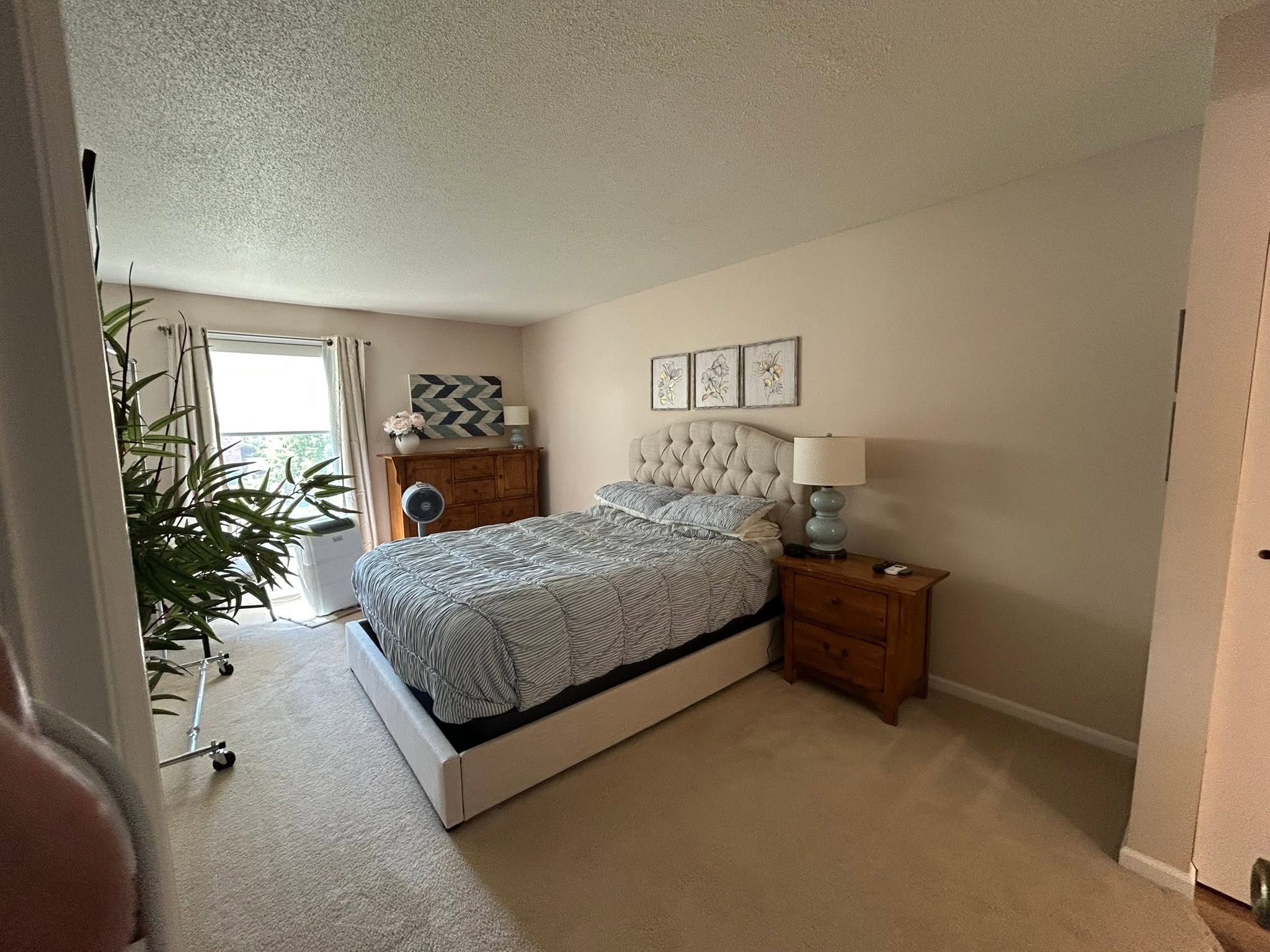 Move-in ready bedroom: made platform bed, dusted nightstand, and clean carpet