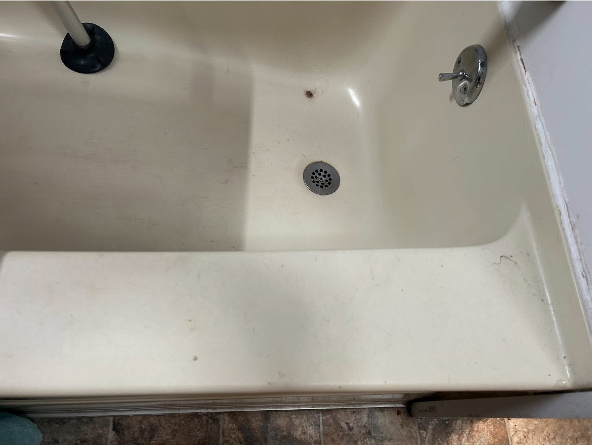 Bathtub with hair and grime around the drain before cleaning