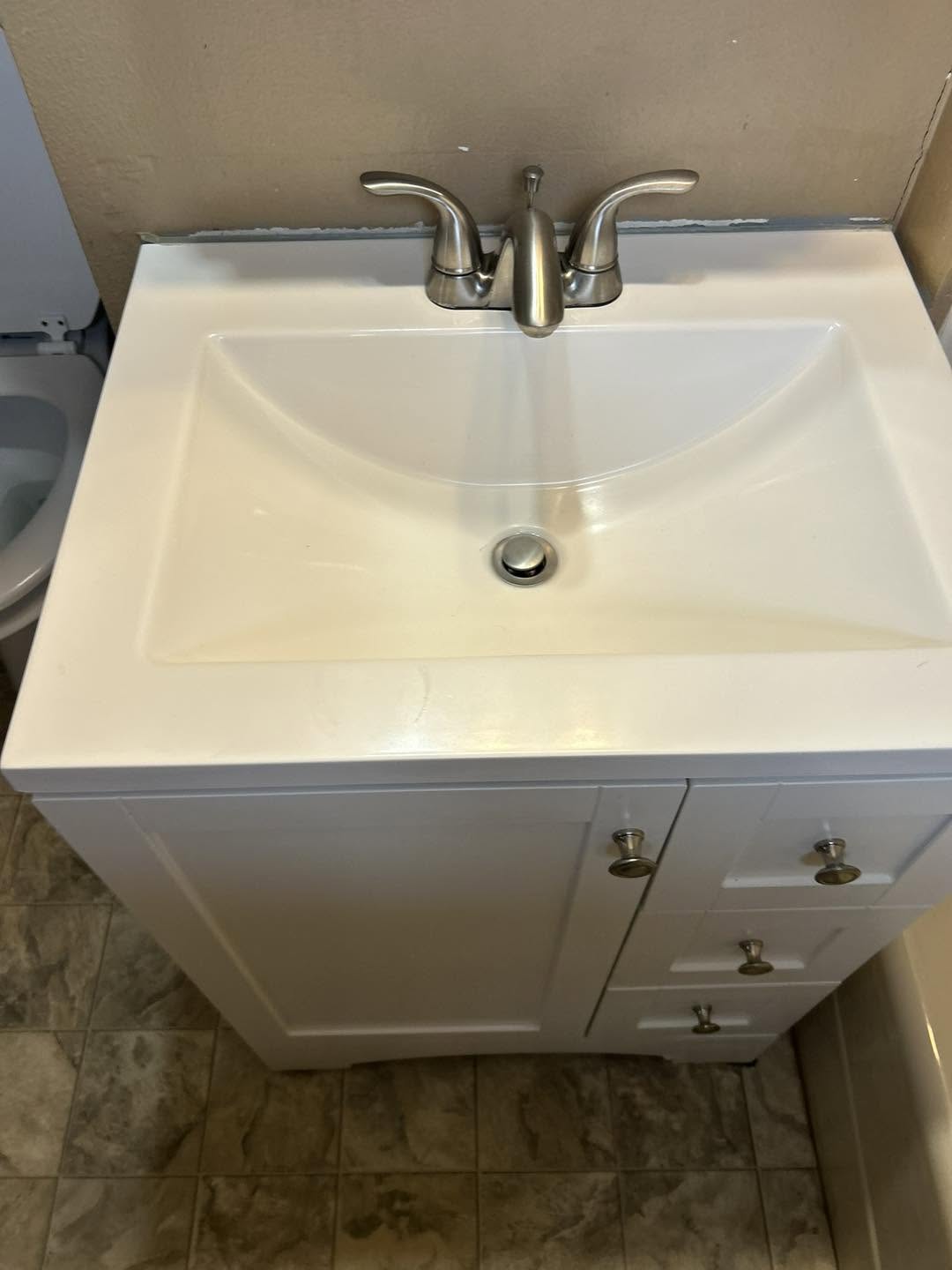 White bathroom vanity and basin wiped clean around a brushed nickel faucet